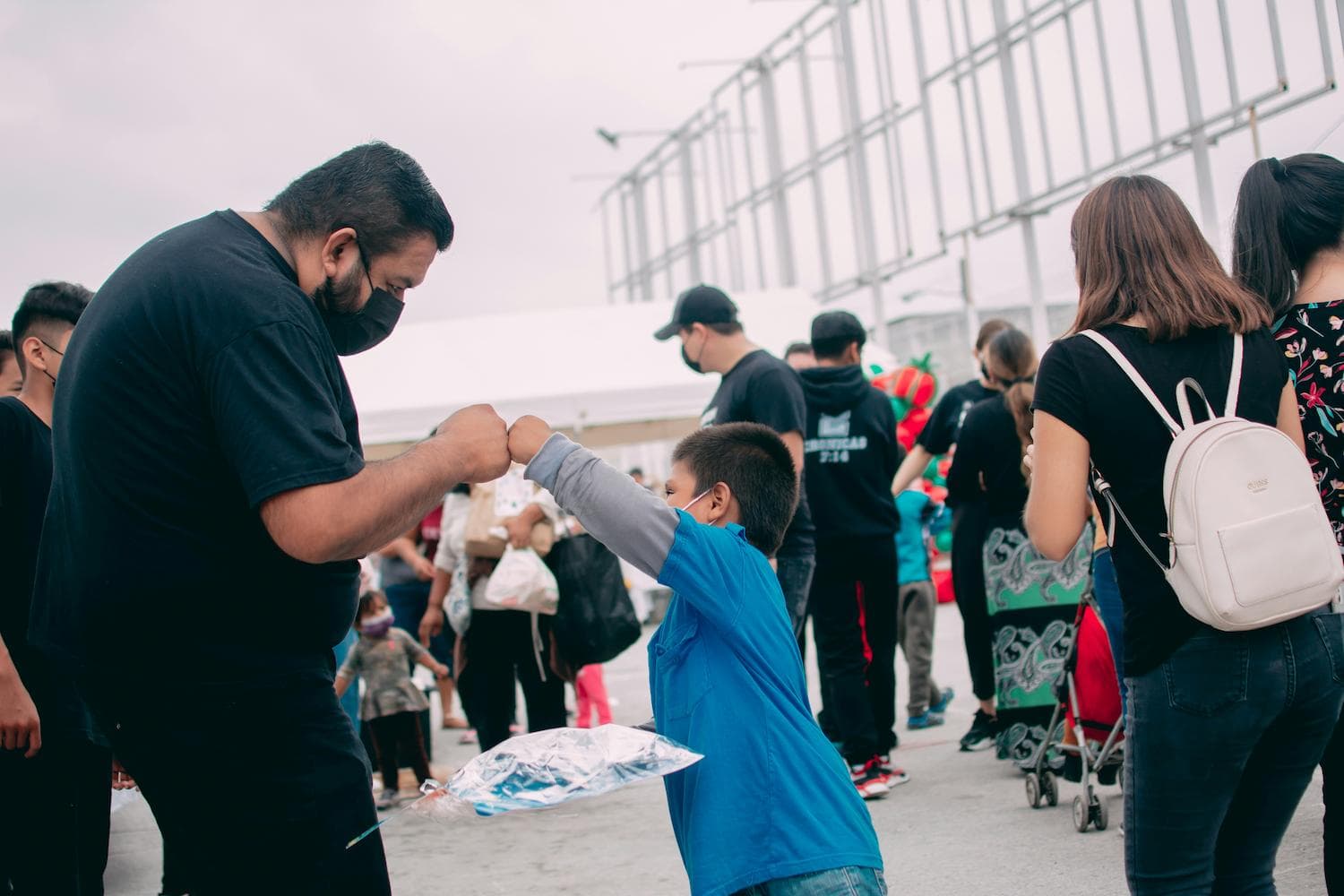 An adult and child bumping fists at an outdoor gathering