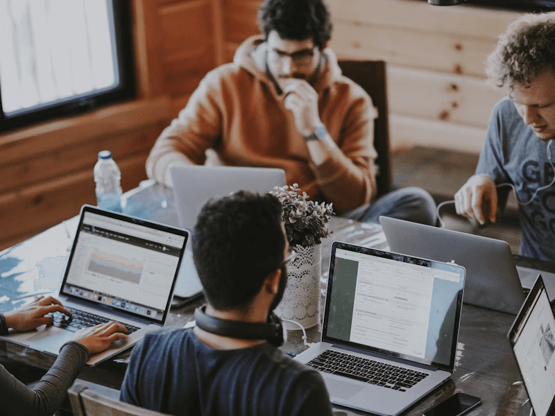 A group working on laptops around a shared table
